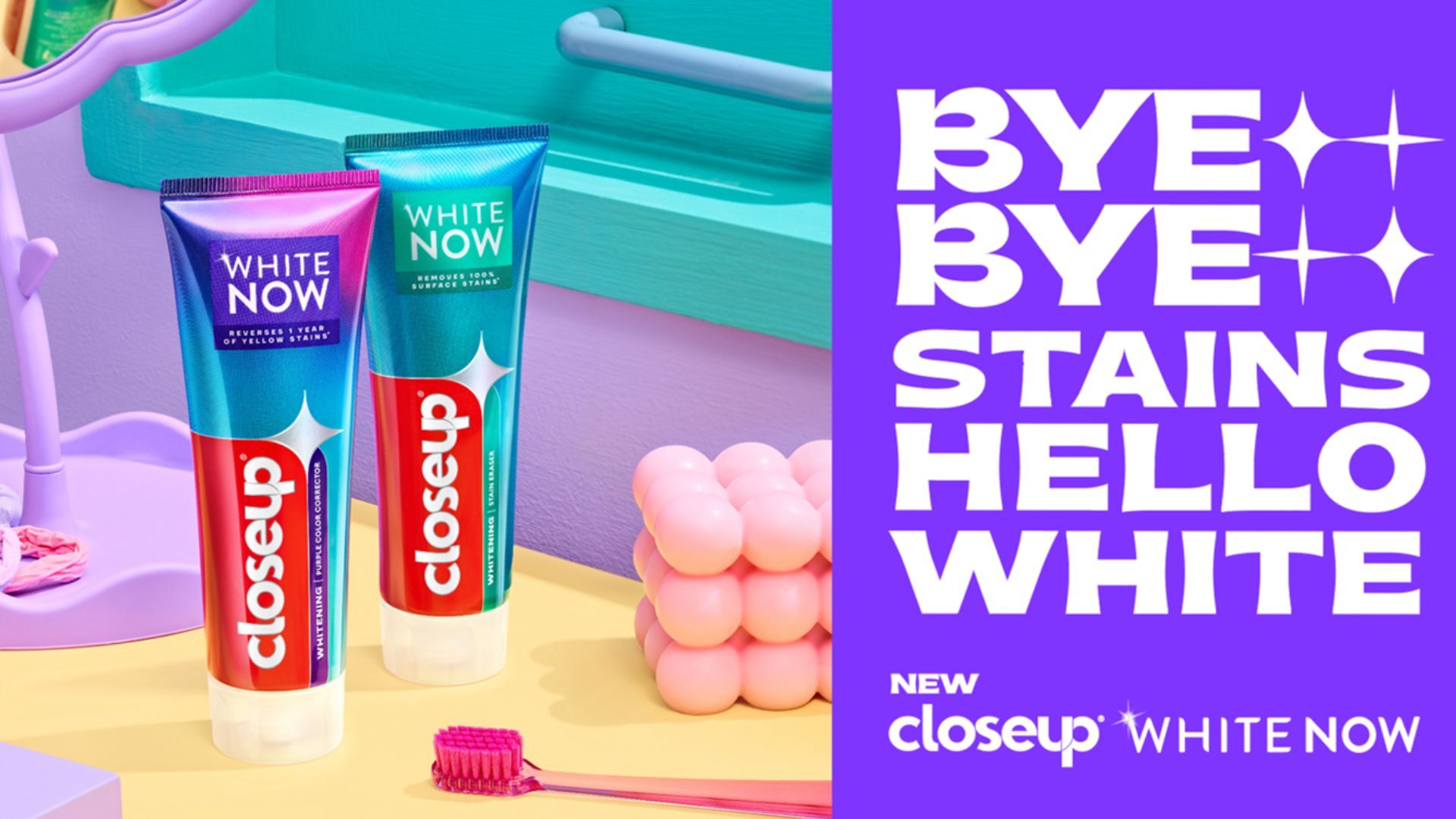 ยาสีฟัน Closeup White Now สองหลอดวางอยู่บนพื้นสีพาสเทลข้าง ๆ แปรงสีฟันสีชมพู หัวเรื่องมีใจความว่า: "โบกมือลาคราบสกปรก สวัสดีความขาวสะอาด" เป็นตัวอักษรสีขาวบนพื้นหลังสีม่วงสดใส
