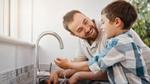 พ่อและลูกชายยิ้มแย้มขณะล้างมือที่อ่างล้างมือ