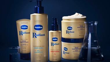ผลิตภัณฑ์จากคอลเลกชัน Radiant X ของวาสลีนประกอบด้วยโลชั่นบำรุงผิวและน้ำมันบำรุงผิวให้ความชุ่มชื้น บรรจุภัณฑ์เป็นสีทองโดยมีพื้นหลังสีน้ำเงินเข้ม