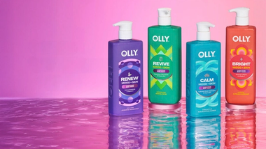 ขวดเจลอาบน้ำ Olly Mood + Skin ที่มีสีสันสดใส 4 ขวดวางอยู่บนพื้นผิวสะท้อนแสง โดยมีพื้นหลังสีชมพูไล่ระดับ